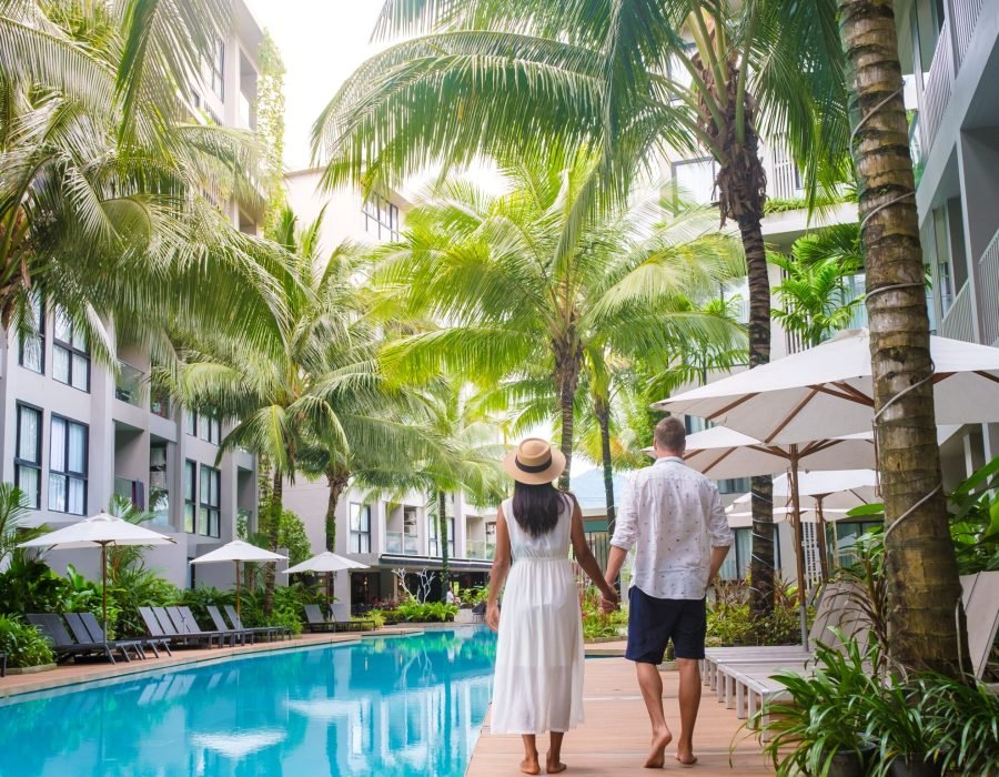Men and women with hat walk by the pool during a vacation in the morning sun